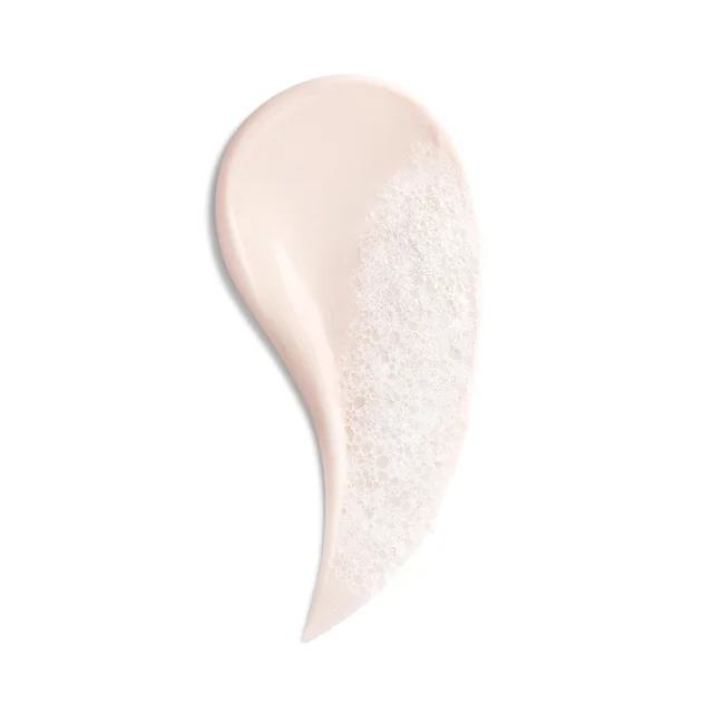 A smear of Biotherm Biosource Softening Foaming Cleanser on a white background, showing a smooth, pale pink cream texture on one side and a bubbly, foamy lather.